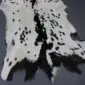 Natural goatskin rug with white fur and black speckled markings.