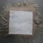 Underside of a square taupe Icelandic sheepskin seat pad showing the light grey leather backing and long wool fringe.