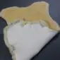 Yellow medical Relugan sheepskin rug with a folded corner showing the white leather underside.