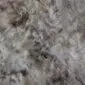 Close up of a rare breed sheepskin rug showing thick, textured wool in mottled grey, cream and brown tones.
