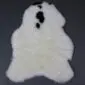 Shorn Icelandic sheepskin rug in off-white with natural black spots and an irregular organic shape.