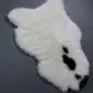 Shorn Icelandic sheepskin rug in cream with natural black spots and an irregular organic shape.