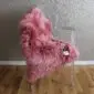Long-pile pink sheepskin rug with a natural organic shape laid flat.