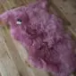 A natural-shaped, long-pile pink sheepskin rug with a thick, curly texture.