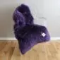 Deep purple sheepskin rug with long, thick wool laid flat.