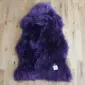 A deep purple sheepskin rug with long, thick wool fibres and a natural pelt shape.
