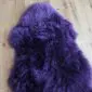 A fluffy, deep purple sheepskin rug with a natural pelt shape and long wool fibres.