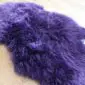 A fluffy, deep purple sheepskin rug with long, textured wool fibres.