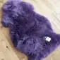 A deep purple sheepskin rug with long, thick wool and a natural organic shape.