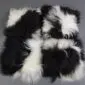 Square Icelandic sheepskin cushion with long, shaggy wool in a black and white spotted pattern.