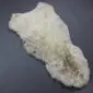 Irregularly shaped rare breed sheepskin rug with thick cream and grey wool pile.