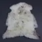 Natural cream rare breed sheepskin rug with grey and brown markings and a thick, textured wool pile.
