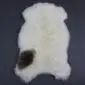Natural white rare breed sheepskin rug with a single dark brown patch on the lower left side.