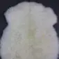 Natural cream and white rare breed sheepskin rug with thick, textured wool and an organic shape.