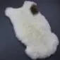 Natural cream sheepskin rug with a single dark brown patch and thick, textured wool.