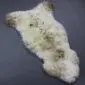 Natural cream sheepskin rug with grey and brown mottled markings and long, textured wool.