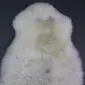 Natural cream rare breed sheepskin rug with subtle grey and tan markings and a thick, textured wool pile.