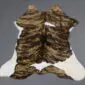 Natural calfskin rug with brindle brown and black stripes over a white base, shown from above on a grey background.