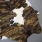 Natural calfskin rug with a brindle pattern of brown and black stripes on a white base.