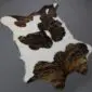 Natural calfskin rug with white and dark brown brindle patches in an irregular hide shape.