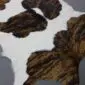Close-up of a white calfskin rug with dark brown and black brindle patches.