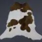 Natural calfskin rug with white fur and large brown patches in an irregular organic shape.