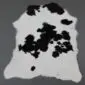 Natural white calfskin rug with large black patches and an irregular organic shape.