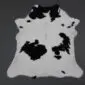Natural calfskin rug with white fur and large black patches in an irregular hide shape.