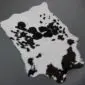 Natural calfskin rug with a white base and irregular black spots and patches.