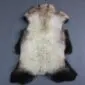 Natural rare breed sheepskin rug with cream wool and dark brown edges in a pelt shape.