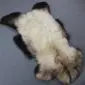 Natural rare breed sheepskin rug with a cream centre and dark brown and grey mottled edges.