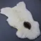 Natural cream rare breed sheepskin rug with a single dark brown spot and thick, textured wool.