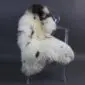 Long-haired rare breed sheepskin rug in cream with dark brown and black spots, laid flat.