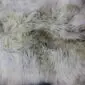 Close-up of a rare breed sheepskin rug with long, thick wool in shades of cream, grey, and light brown.