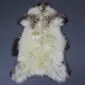 Large rare breed sheepskin rug with long cream wool and dark brown mottled markings along the edges.