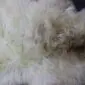 Close-up of a rare breed sheepskin rug showing thick, textured cream and grey wool fibres.