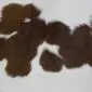 Natural calfskin rug with dark brown and white speckled markings and an irregular organic shape.