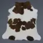 Natural calfskin rug with white fur and dark brown patches in an irregular organic shape.