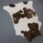 Natural calfskin rug with a white base and dark brown patches in an irregular shape.