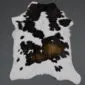 Natural calfskin rug with a white base, black speckled markings and a central brown patch.