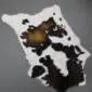 Natural calfskin rug with white, black and tan markings on a grey background.