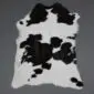 Natural calf skin rug with a black and white speckled pattern and irregular edges.