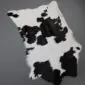 Natural calfskin rug with a white base and irregular black patches.