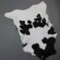 Natural calfskin rug with a white base and irregular black patches. detail view