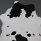 Natural calfskin rug with a white base and irregular black patches.