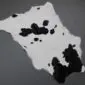 Natural calfskin rug with a white base and irregular black spots.