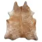 Natural cowhide rug with an exotic beige and tan speckled pattern and irregular organic shape.
