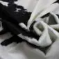 Close-up of a folded black and white cowhide rug showing the natural hair texture and suede underside.