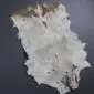 Natural goatskin rug with white fur and brown markings on a dark grey surface.