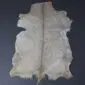 Natural goatskin rug with grey and white mottled fur and a brown stripe down the centre.